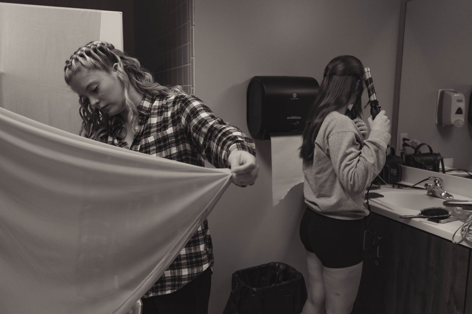 Black and white photo of two women getting ready in a bathroom before a wedding ceremony.