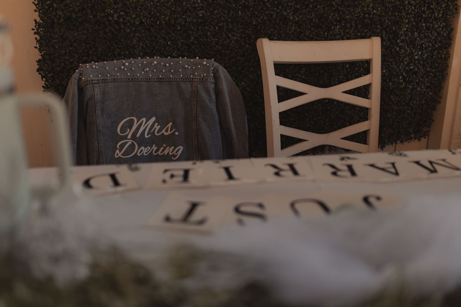 Mrs. Dooring wedding chair sign with Just Married banner at reception table.