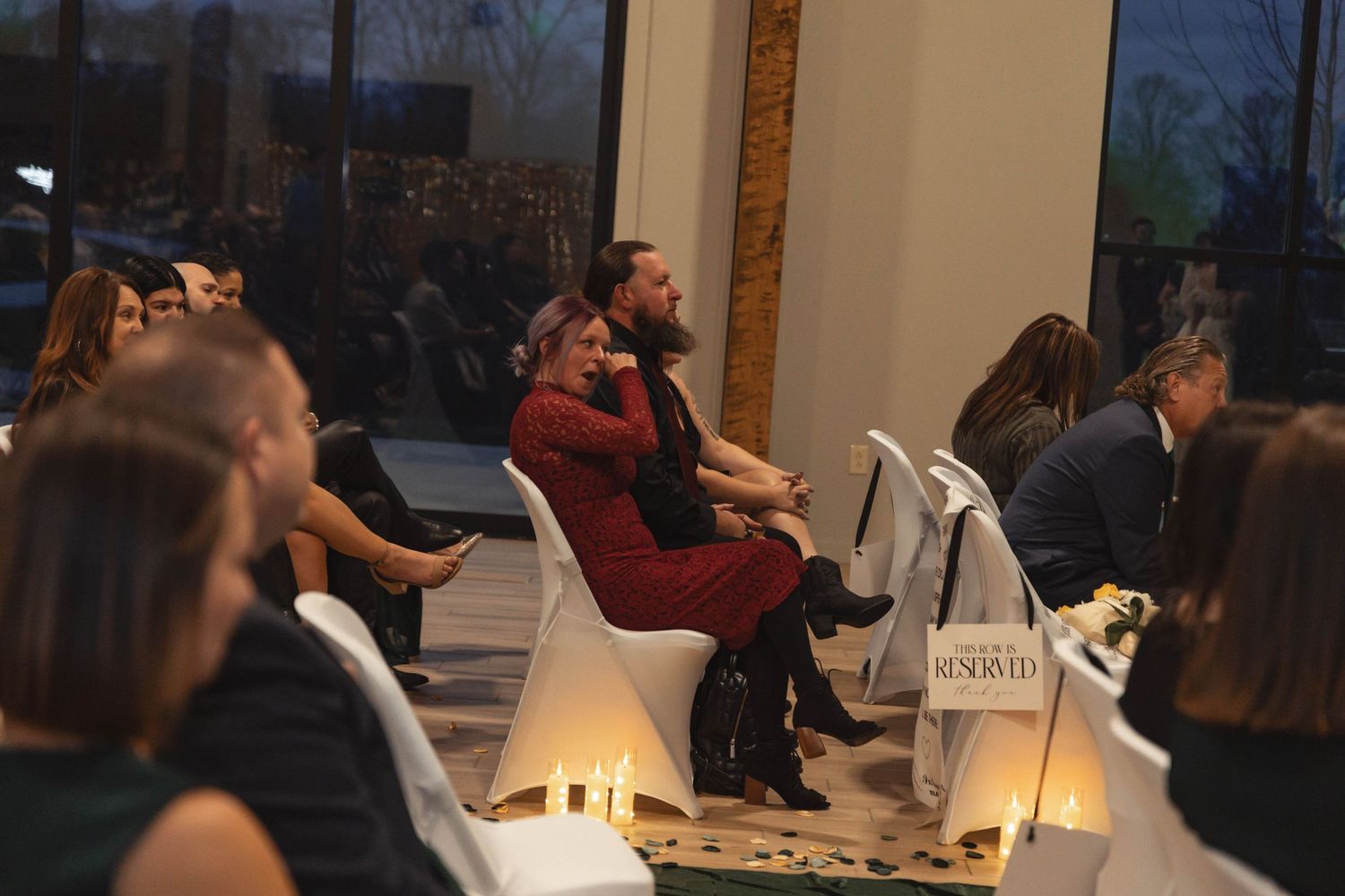 Guests seated at an elegant indoor event venue with candlelit decor and reserved signs.