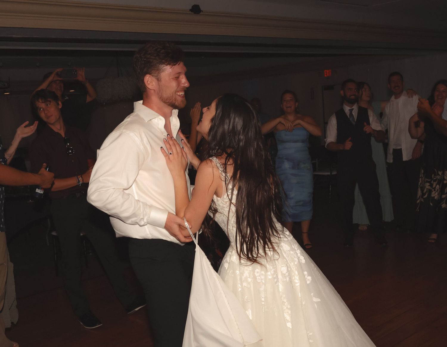 Bride and groom share a romantic dance together on the wedding reception dance floor surrounded by guests.