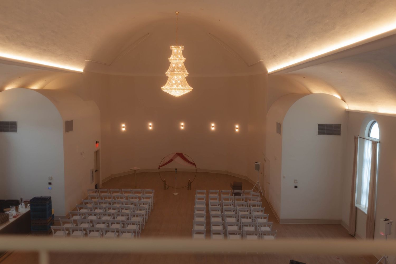 Elegant wedding venue with vaulted ceilings, chandelier, and rows of white chairs set for a ceremony.