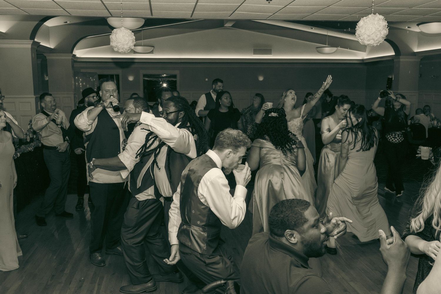 Lively black and white wedding reception dance floor filled with joyful guests celebrating together.