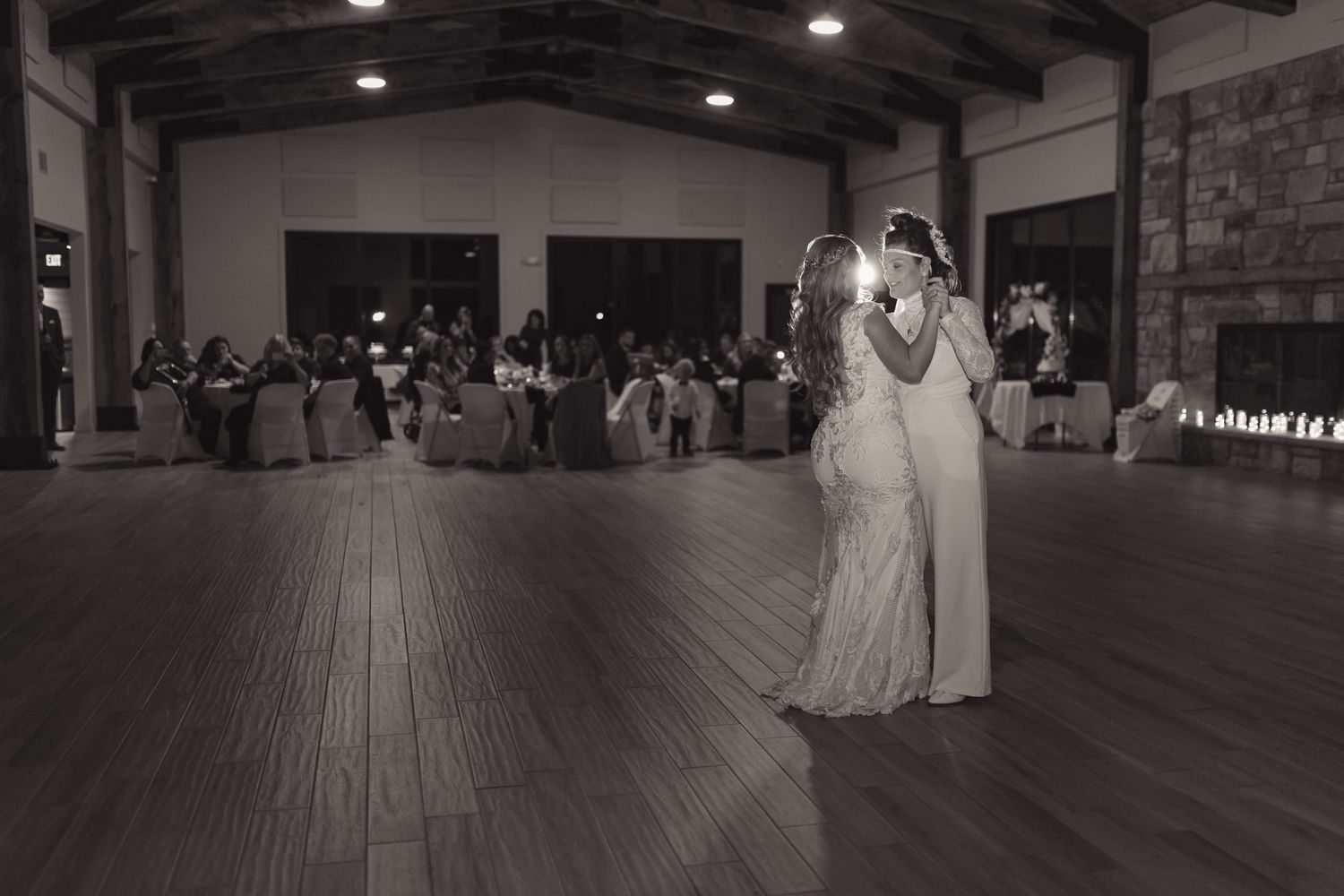 Black and white photo of a bride and groom sharing their first dance at a wedding reception.