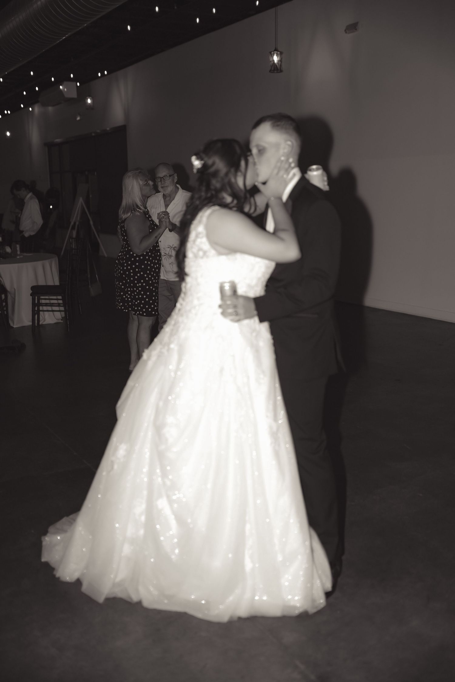 Black and white photo of a bride and groom sharing their first dance at a wedding reception.