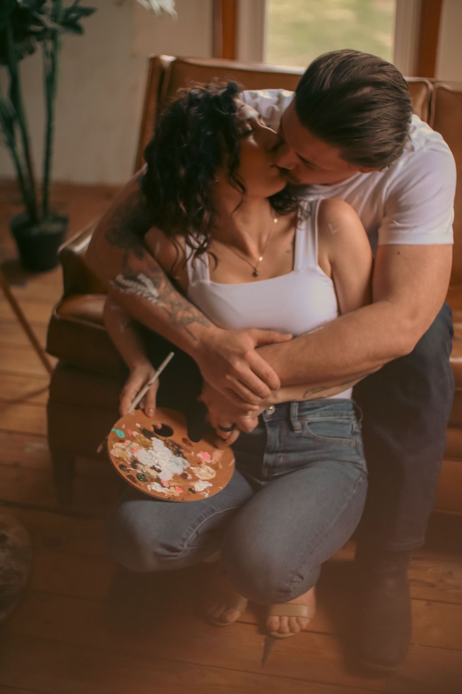 A romantic couple shares an intimate moment while creating art and painting in their cozy home.