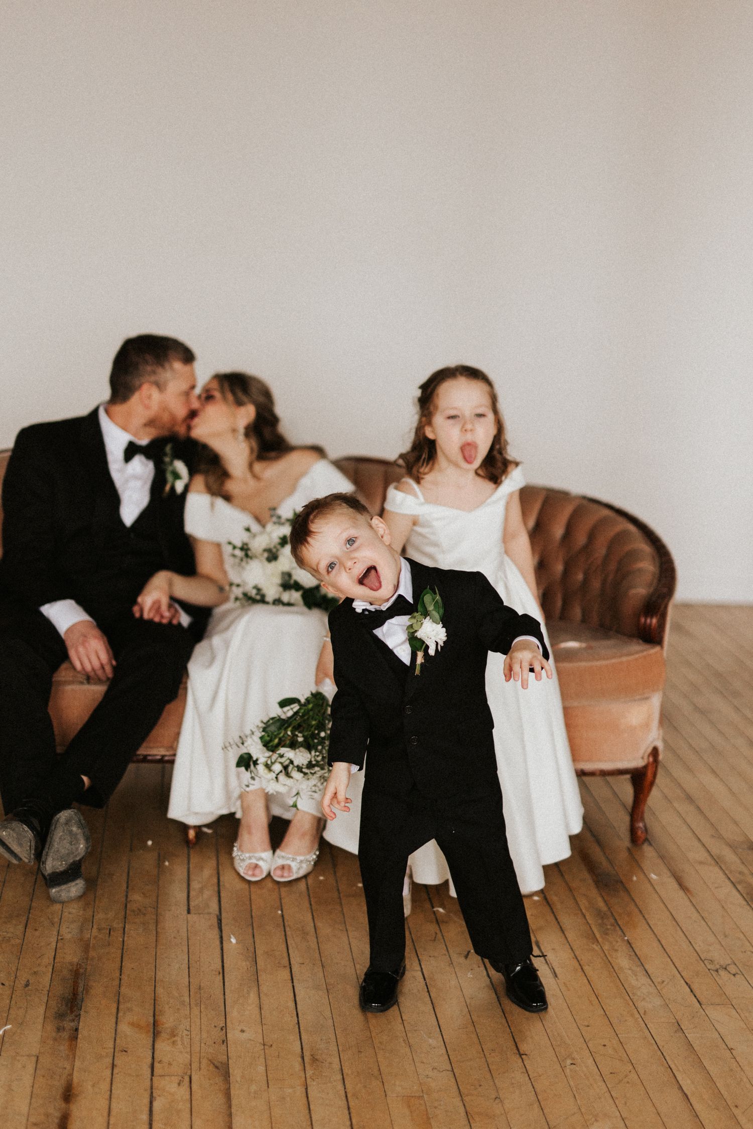 Playful wedding portraits on wooden floor with laughter and candid moments.