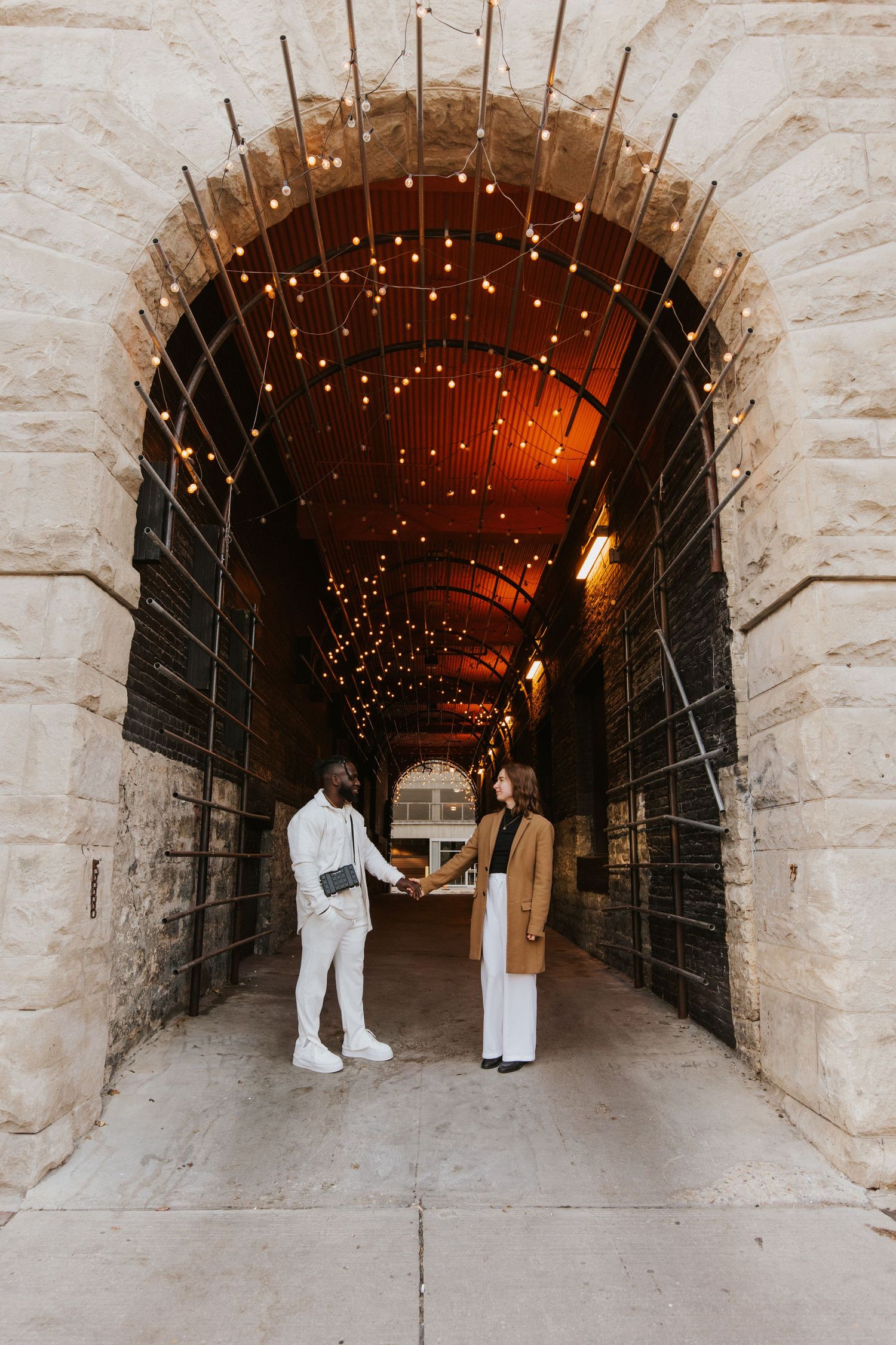 A stone tunnel decorated with romantic string lights creates a magical atmosphere.