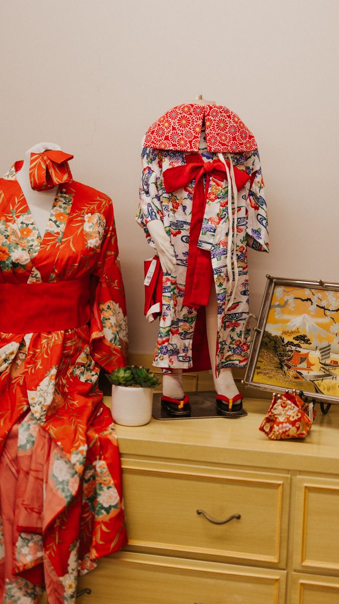 Collection of traditional Japanese kimonos in red and floral patterns displayed on dress forms.