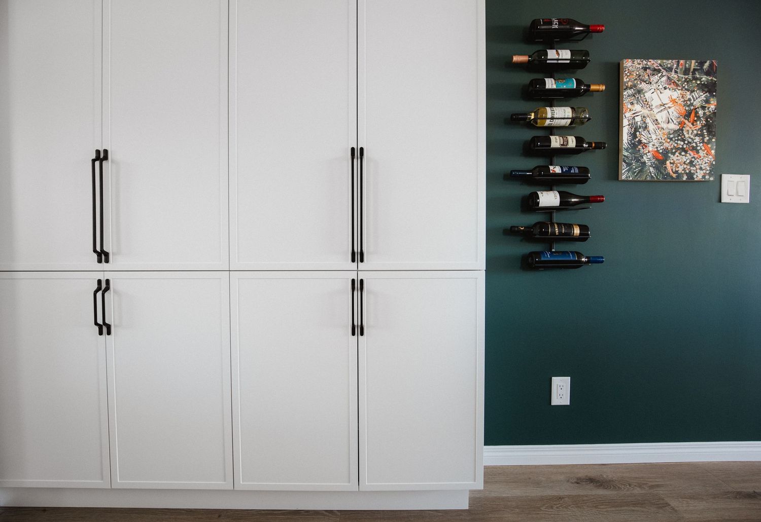 White built-in cabinets with a dark accent wall featuring wine storage.