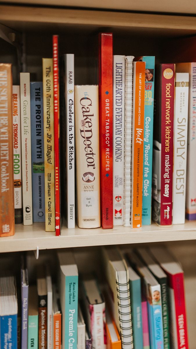 Colorful collection of books arranged neatly on wooden shelves showing various spines and titles.