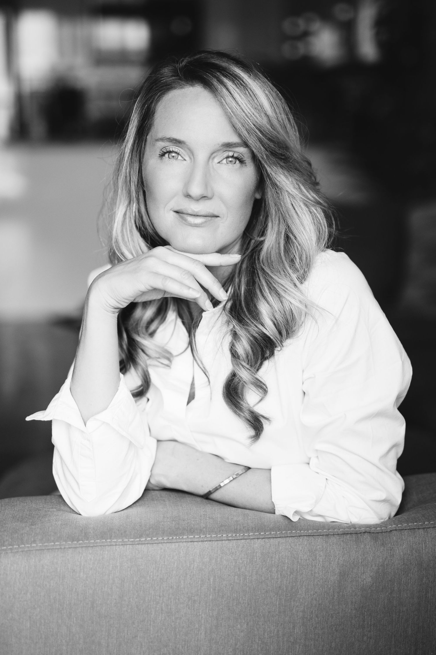 Black and white portrait of someone relaxing on couch in white button-down shirt.