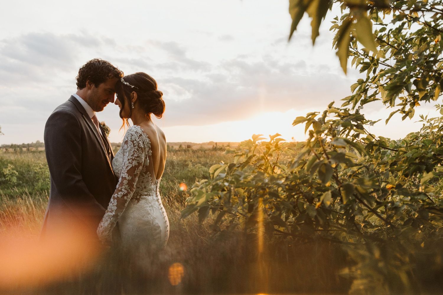 Romantic sunset wedding portrait amidst natural foliage.