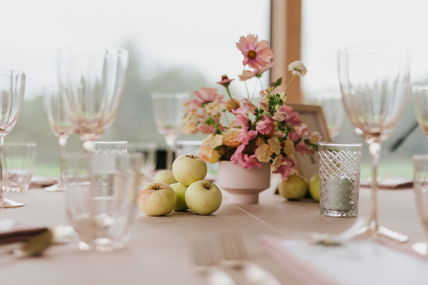 Elegant table setting with pink floral arrangements and crystal glassware at a formal event.