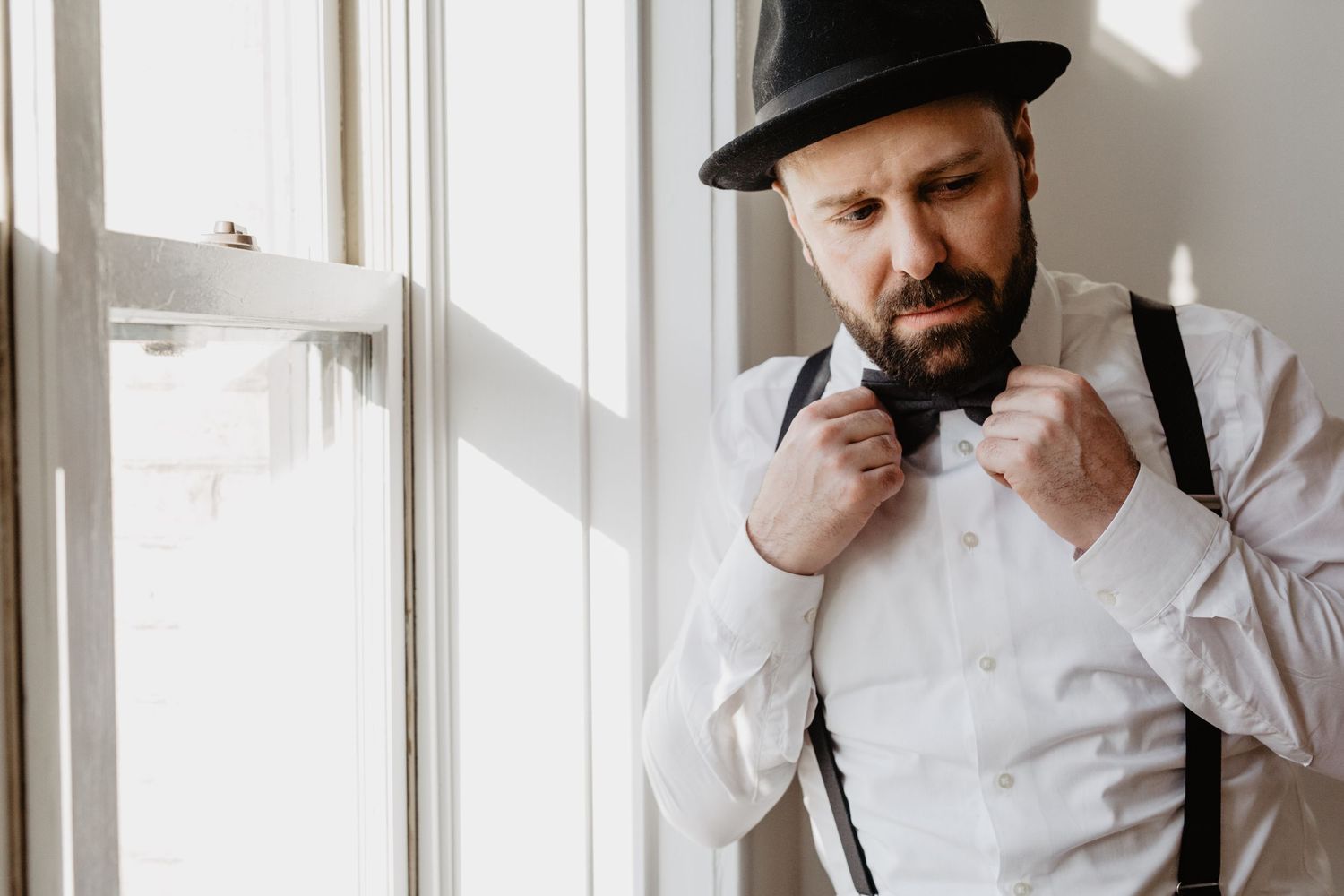 Stylish portrait of person in vintage attire and black hat against white background.