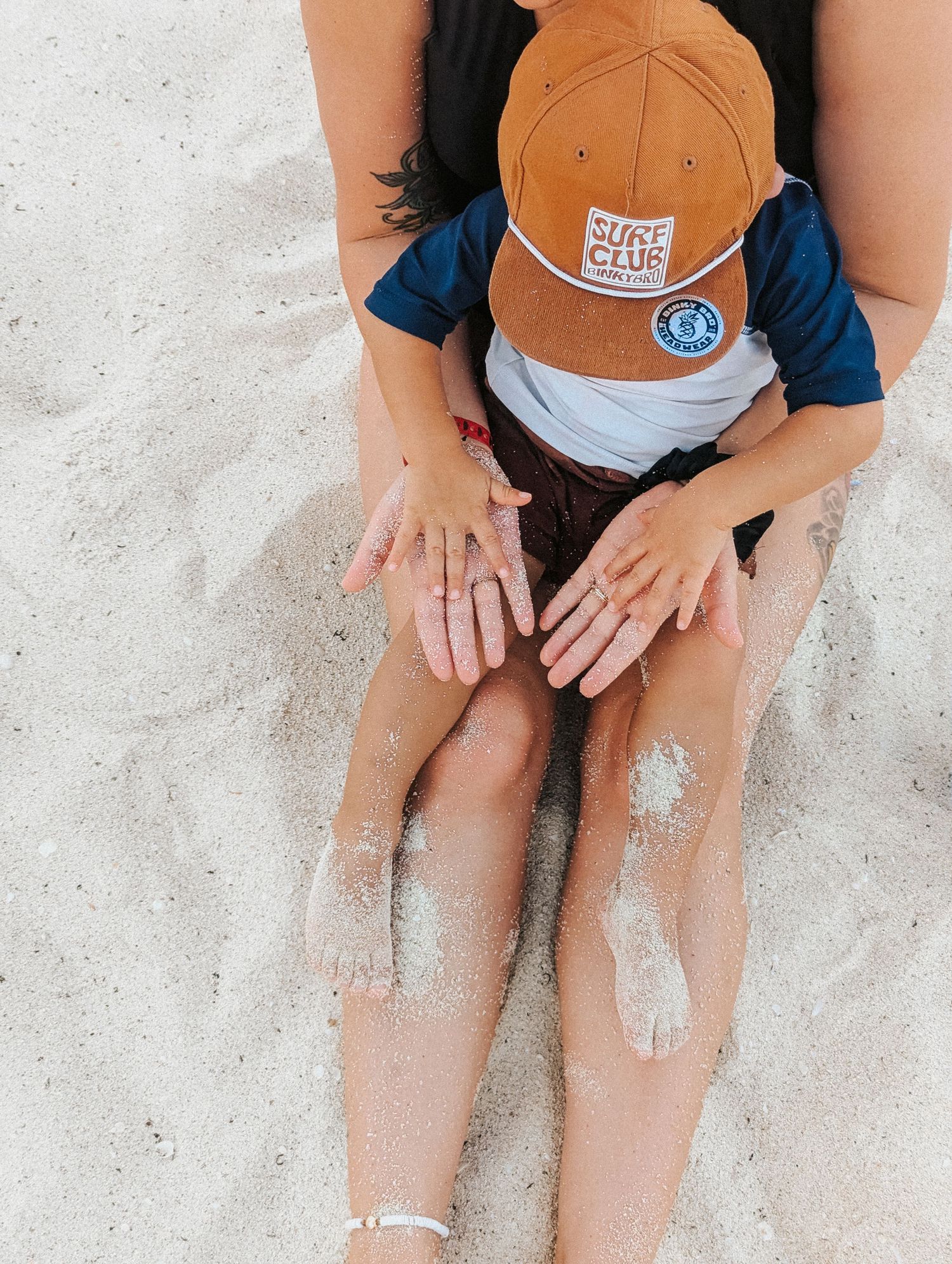 Sandy feet on beach with scattered sand and blue denim visible.