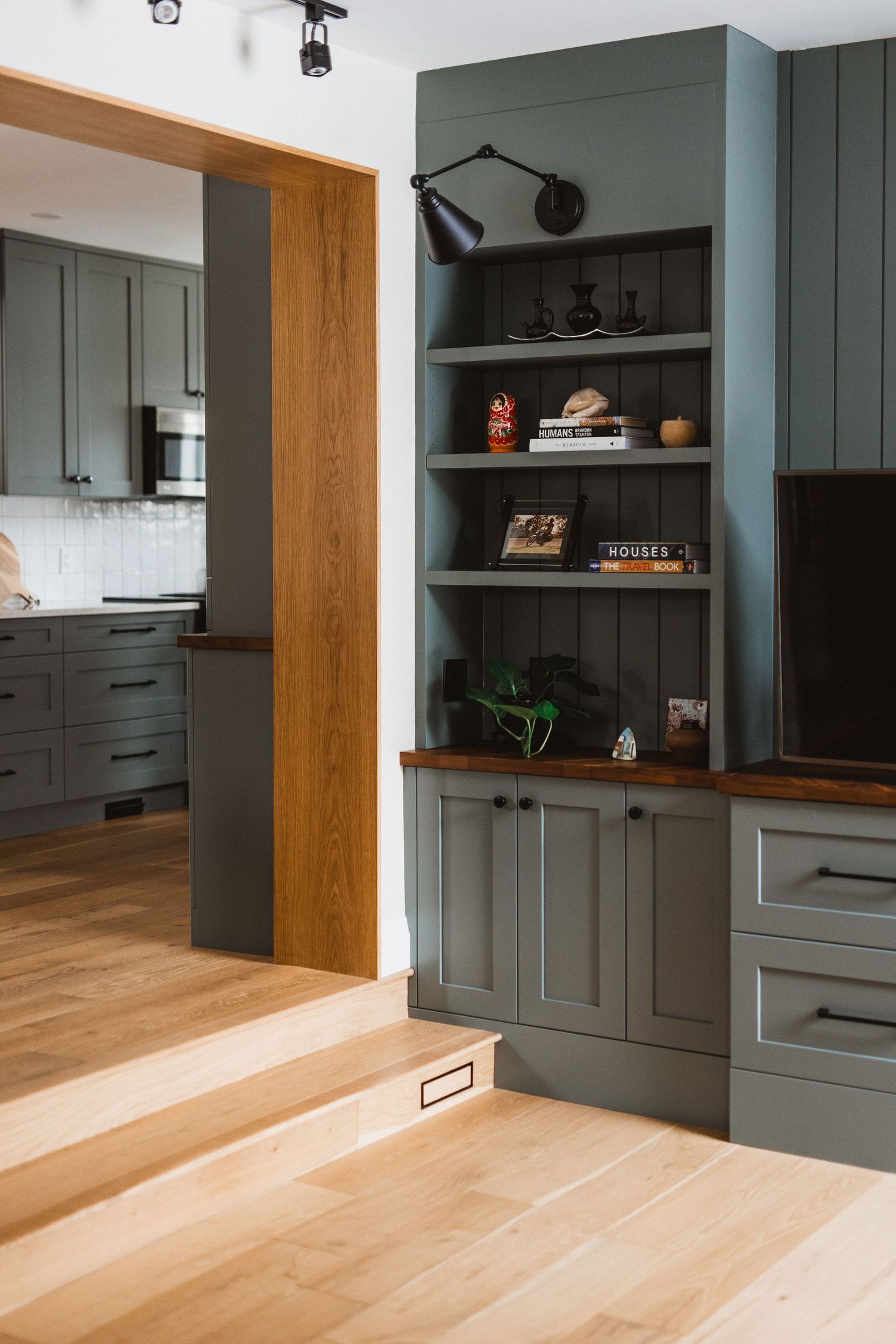 Built-in gray cabinetry with open shelving and natural wood accents in a contemporary living space.