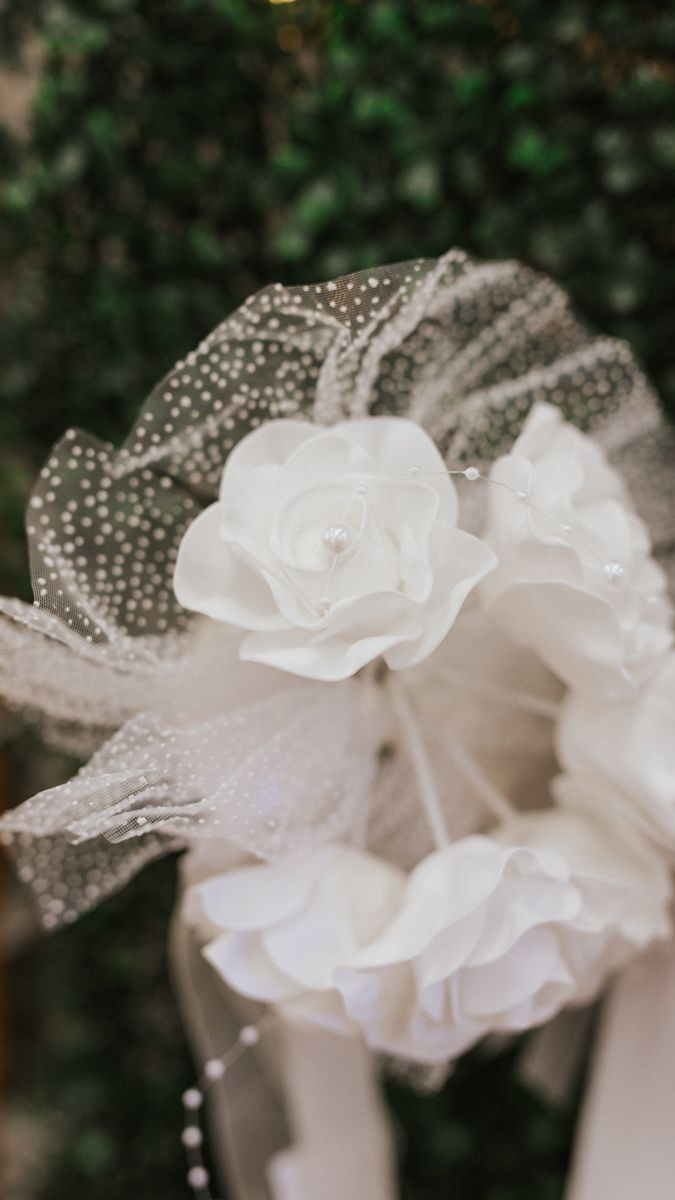 Close-up of delicate white fabric flowers with pearl details and tulle.