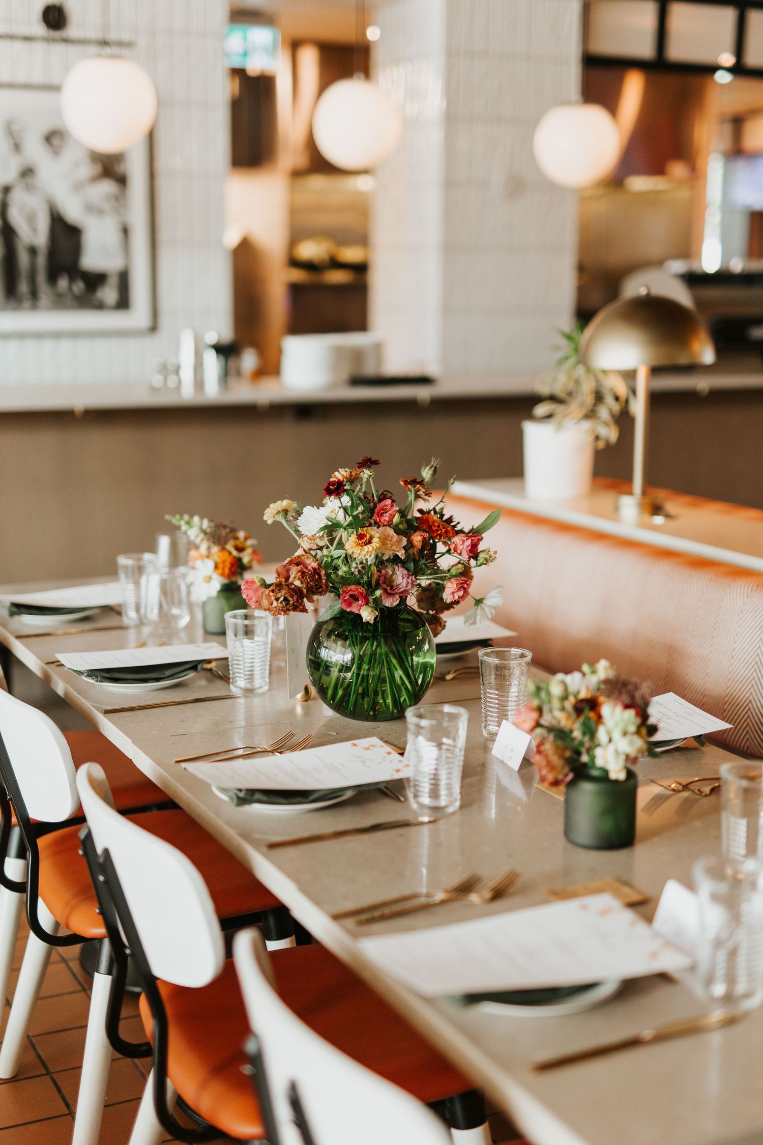 Contemporary dining room setup with white chairs and floral arrangements on wooden tables.