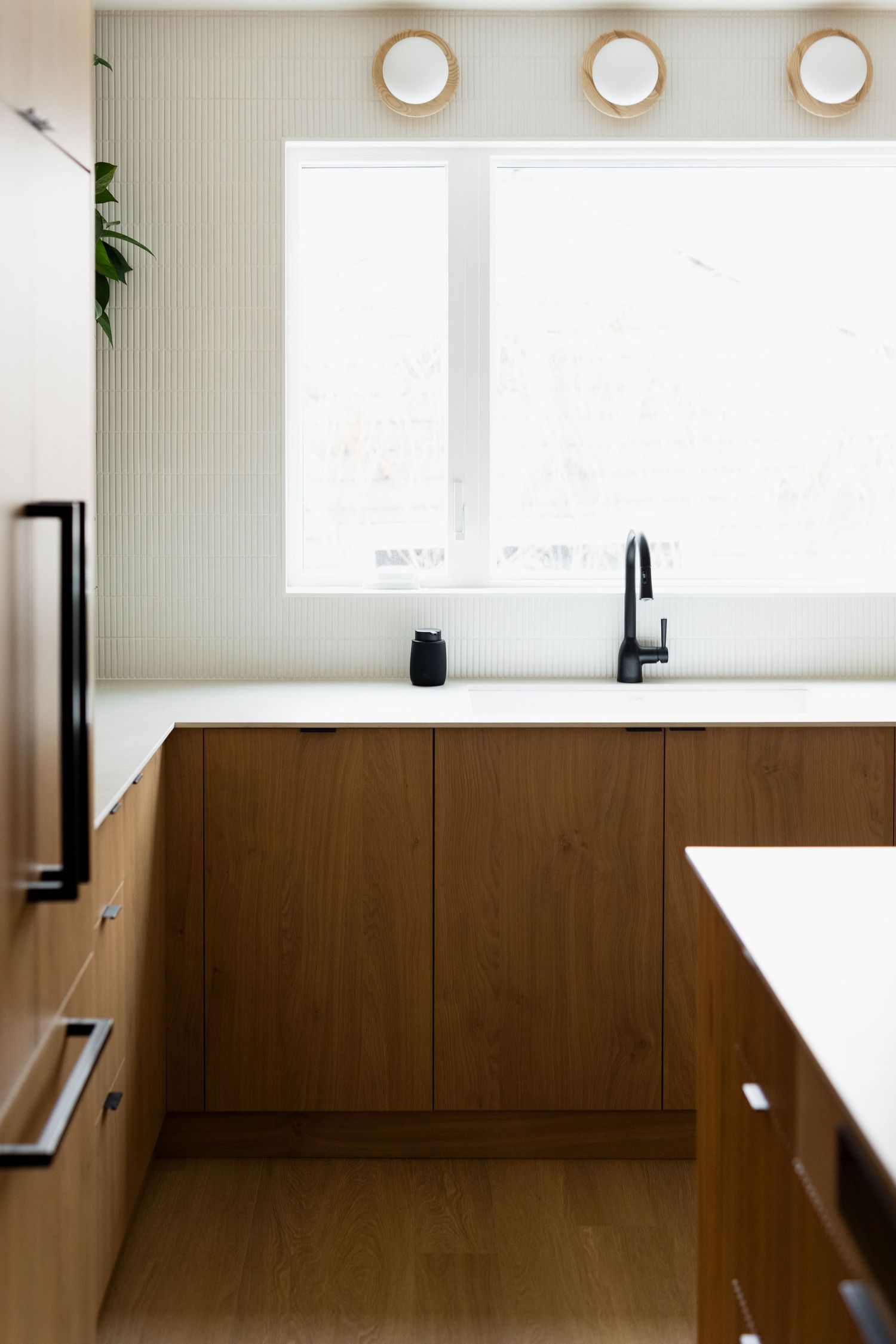 Sleek built-in cabinetry with round decorative wall lights and large windows in modern interior.