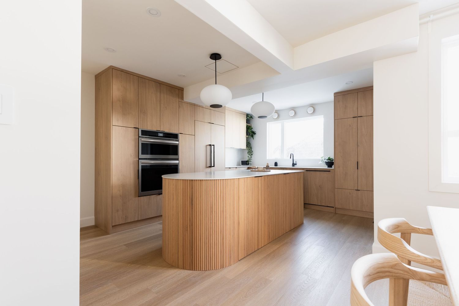 Bright open concept living space with wooden built-ins and white walls creating a minimalist aesthetic.