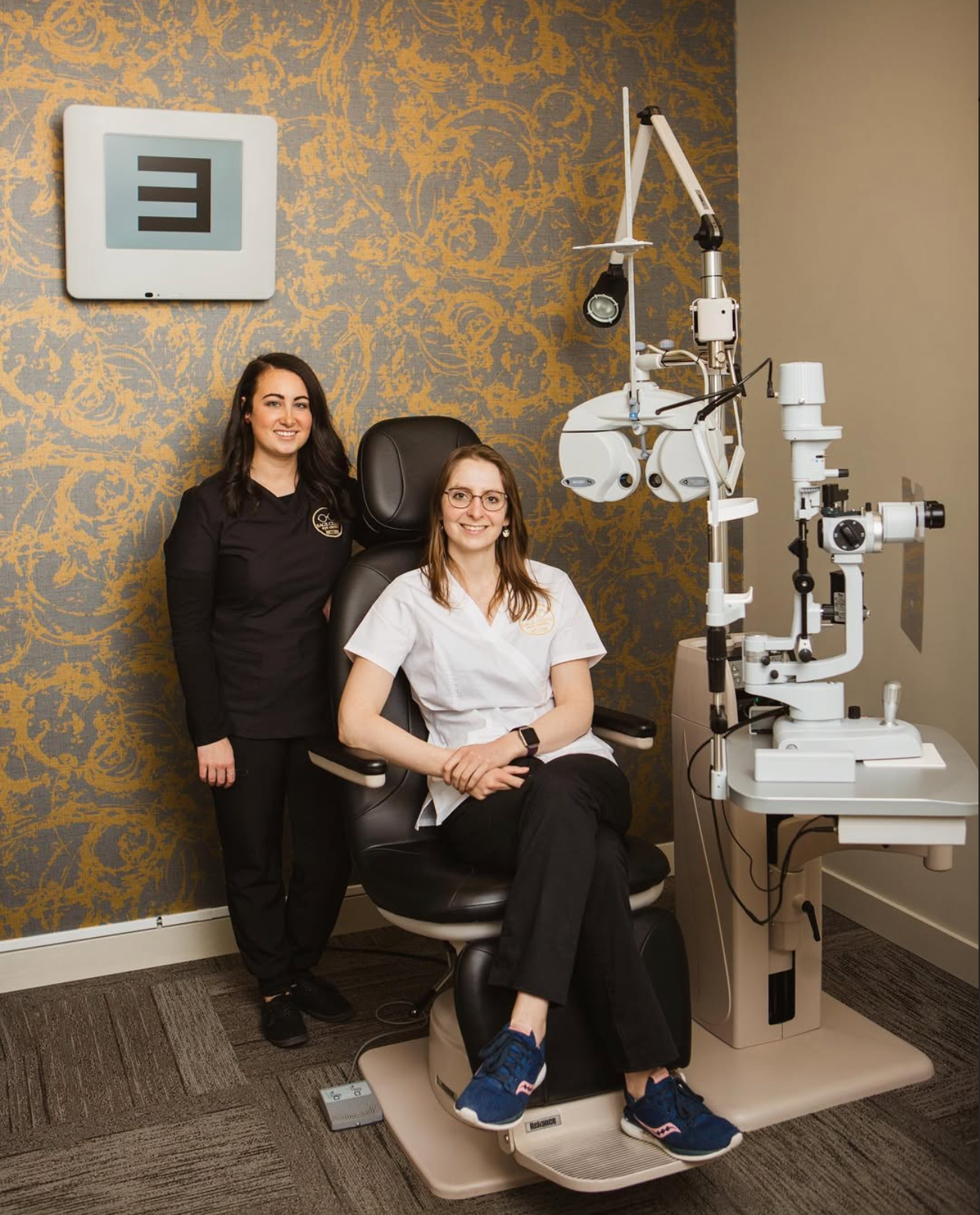 Medical office interior with patterned wallpaper and eye examination equipment.