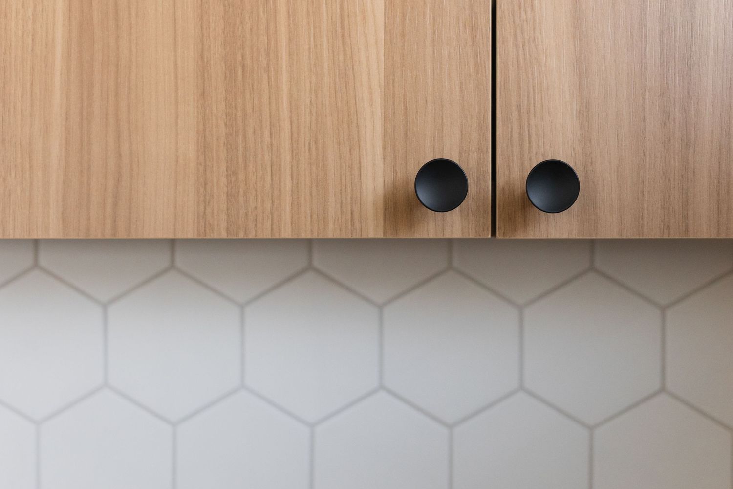 Minimalist wood cabinetry with geometric pattern detail spans across a white interior wall.