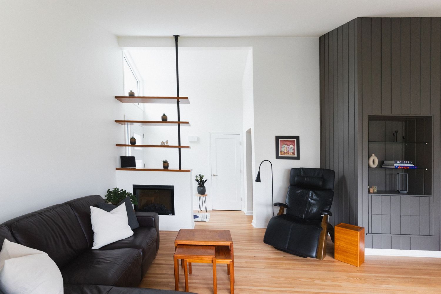 Modern living room with black sofa, wooden furniture, and bright natural lighting.
