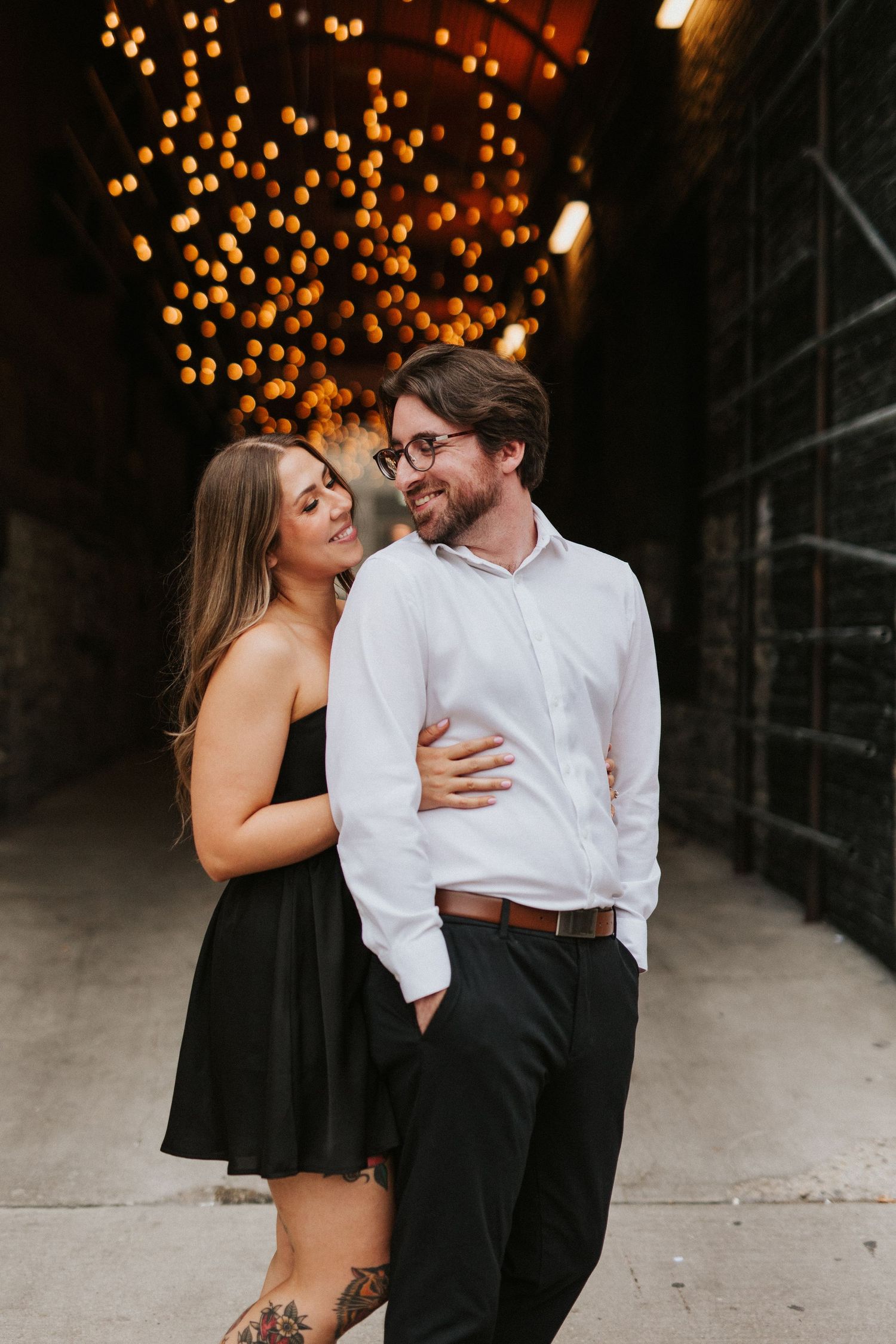 A romantic evening photoshoot features warm bokeh lights and elegant black and white attire.