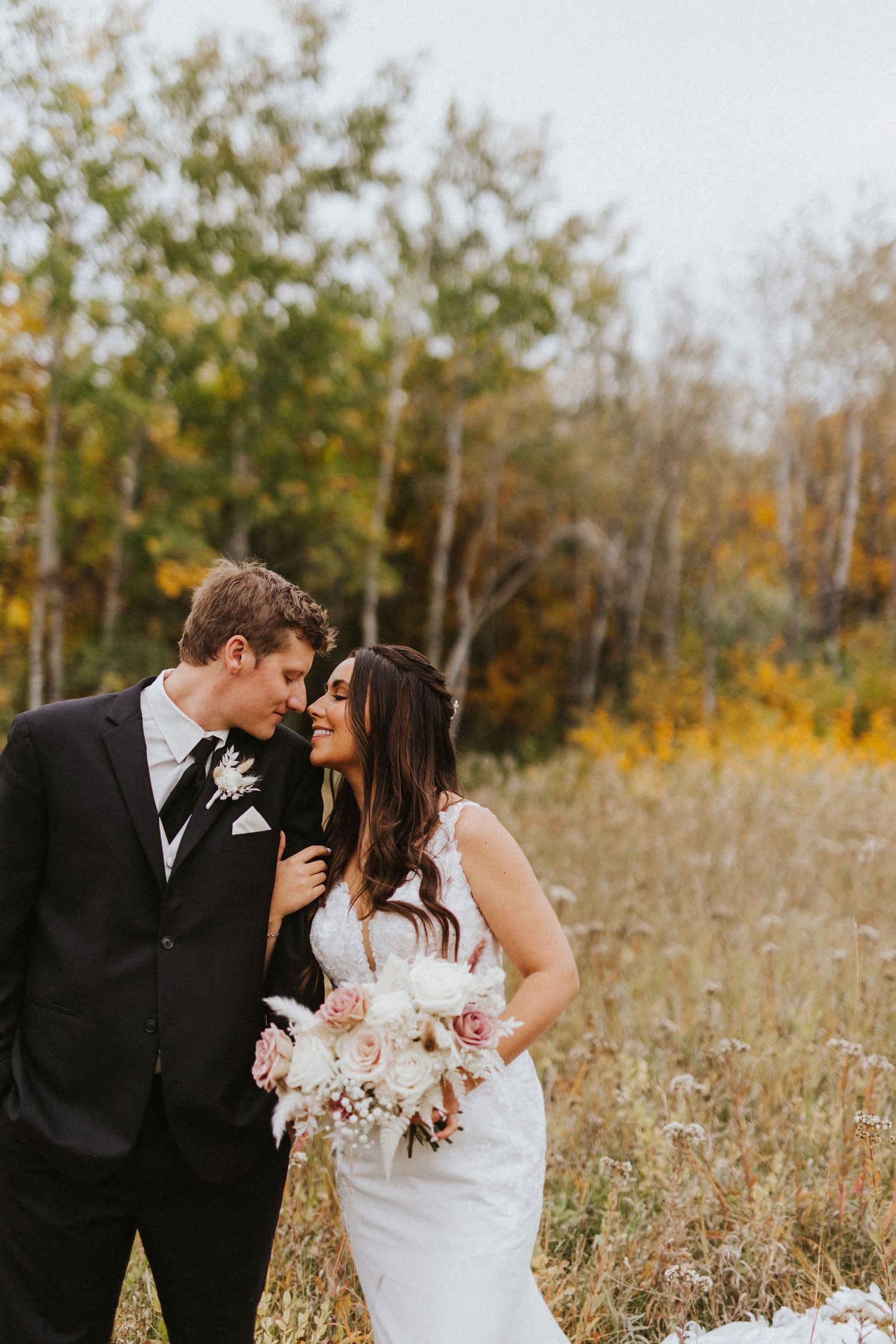 Intimate wedding portrait in autumn field with golden light and white bouquet.
