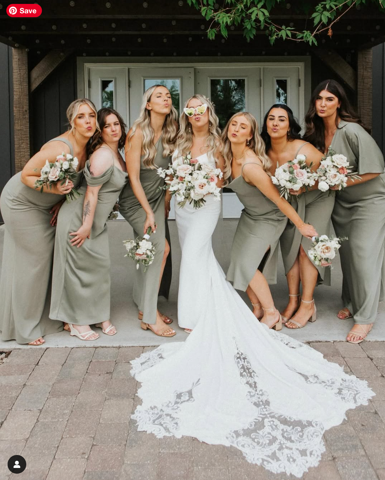 Wedding party in gray dresses displaying the bride's trailing white lace gown.