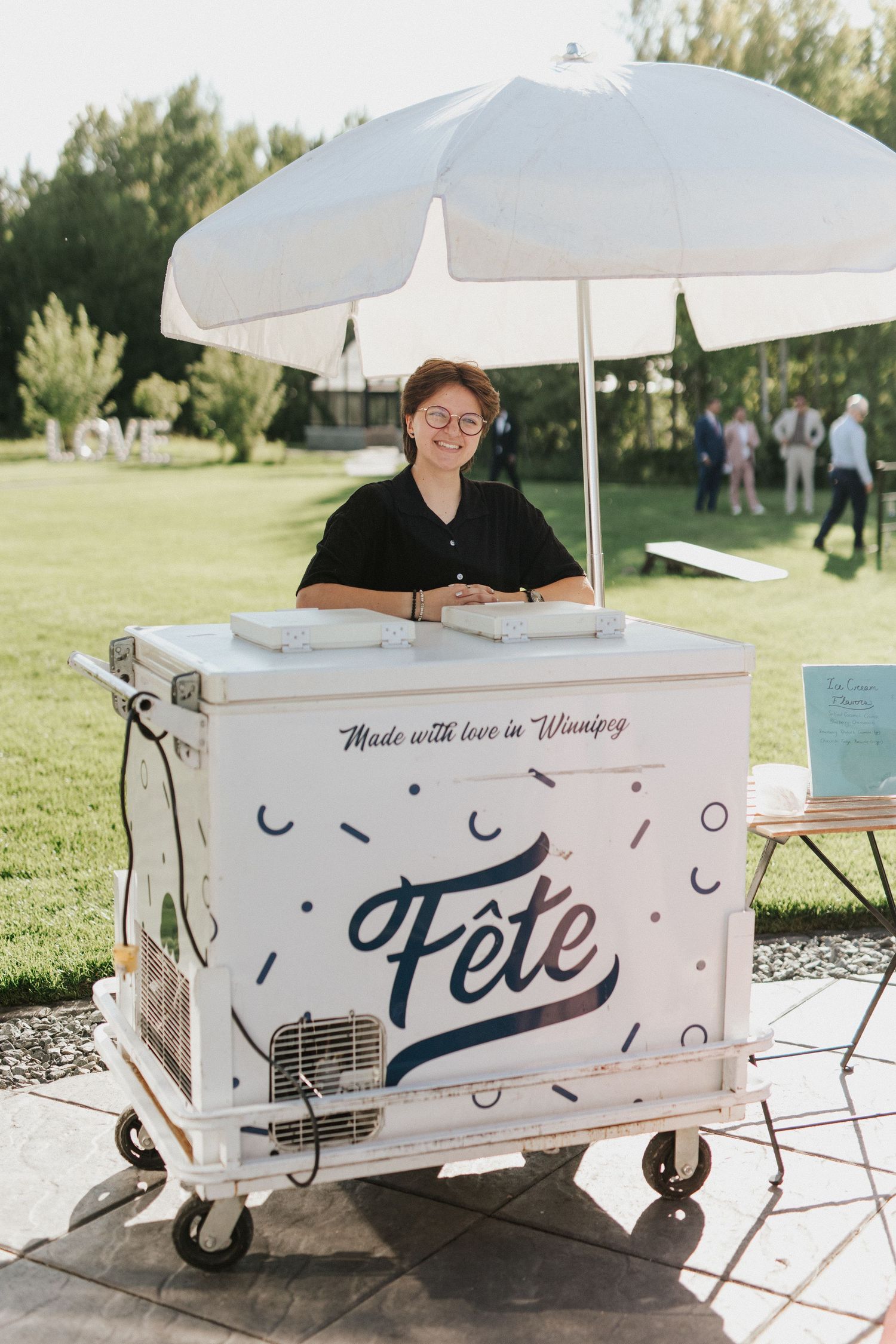 A mobile food cart labeled 'Fete' with a white umbrella serving treats at an outdoor event in Winnipeg.