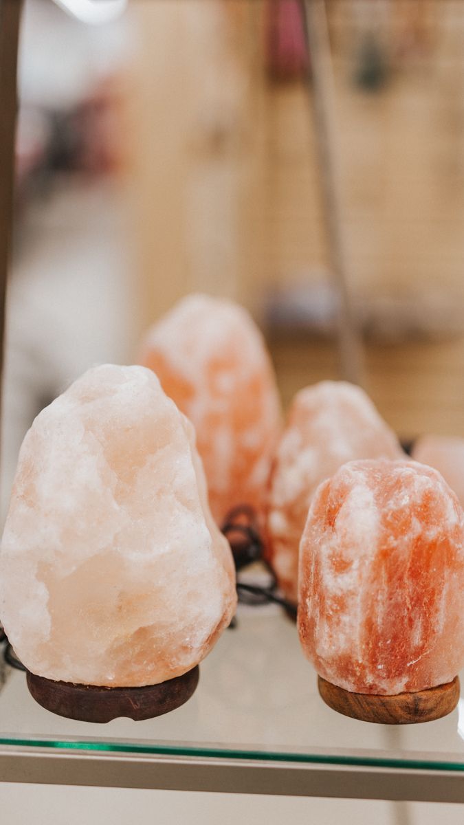 Collection of pink Himalayan salt lamps arranged in a row on glass shelving.
