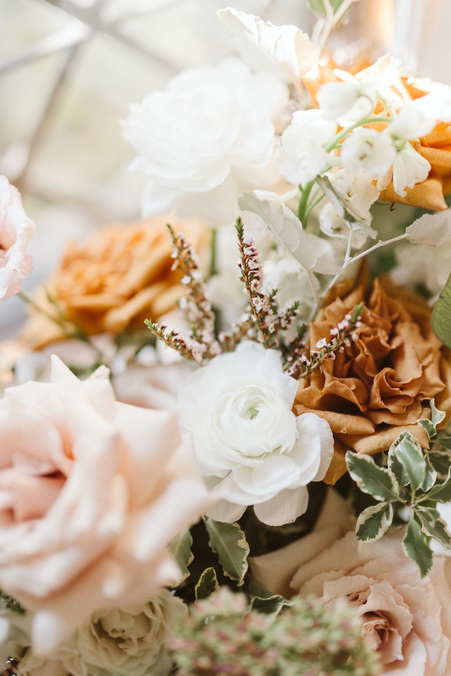Elegant floral arrangement with white and peach roses mixed with delicate greenery.