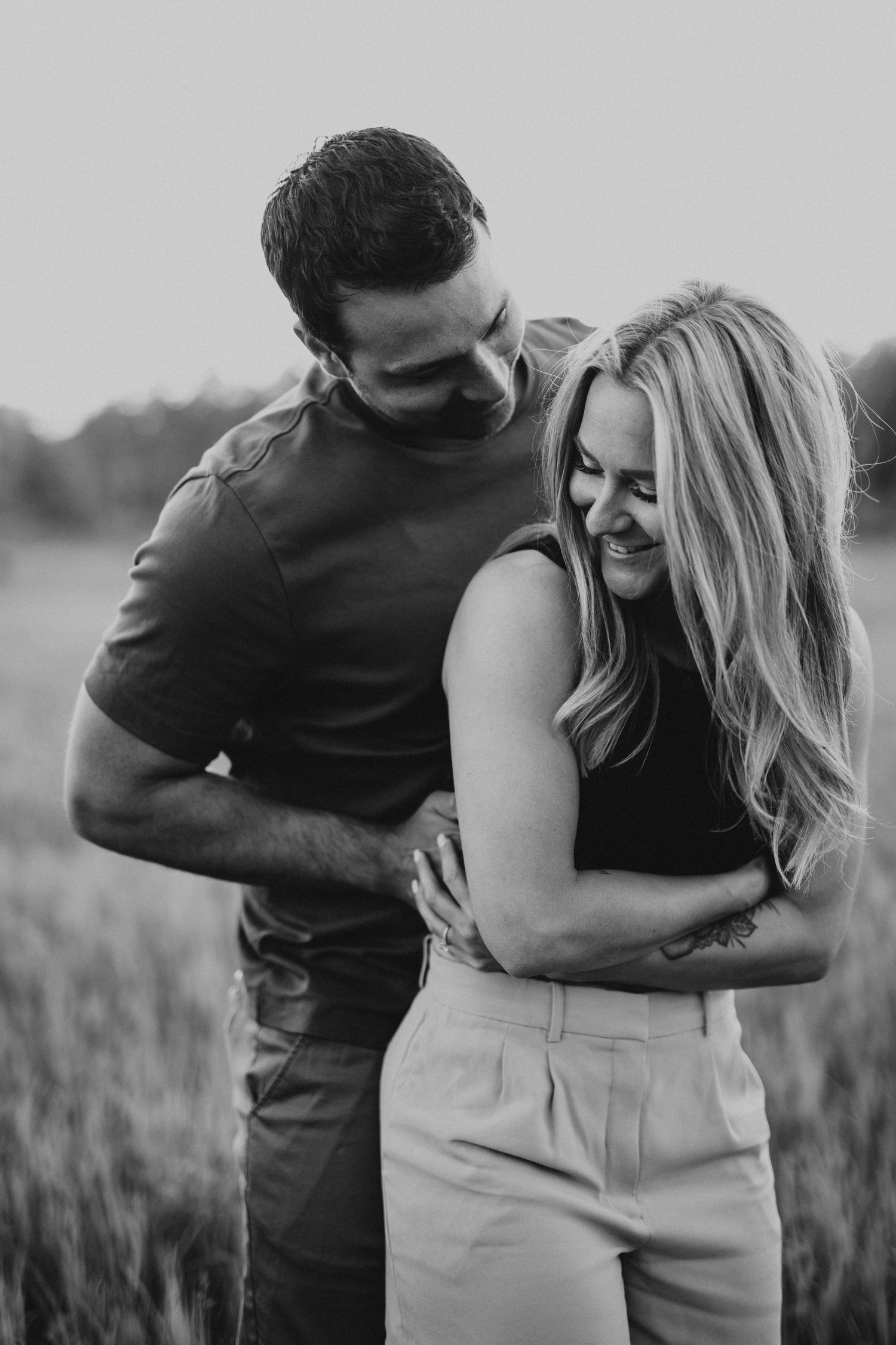 Romantic black and white portrait sequence showing tender embraces in a rustic field setting.