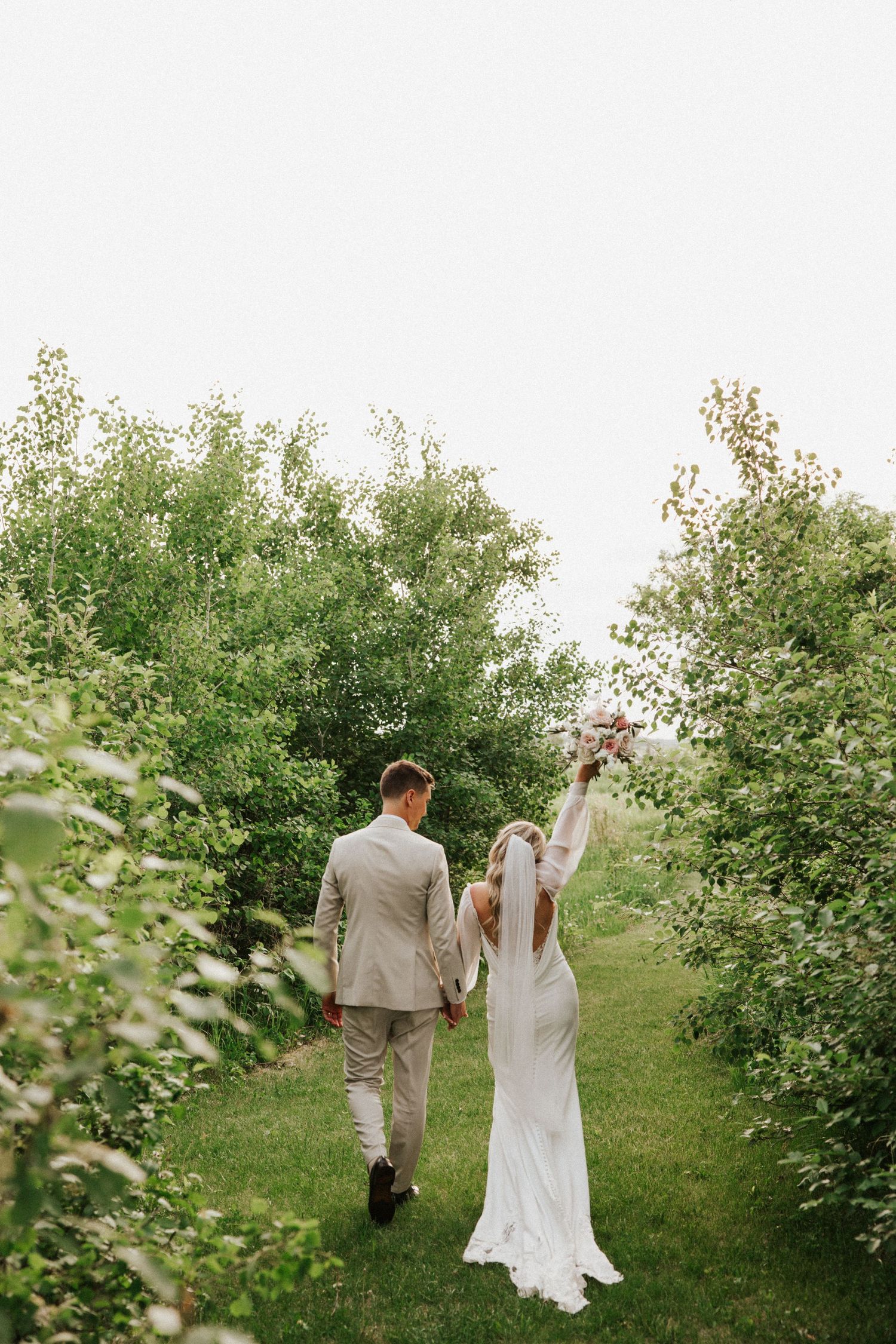 Couple walks through lush garden setting during wedding photoshoot.