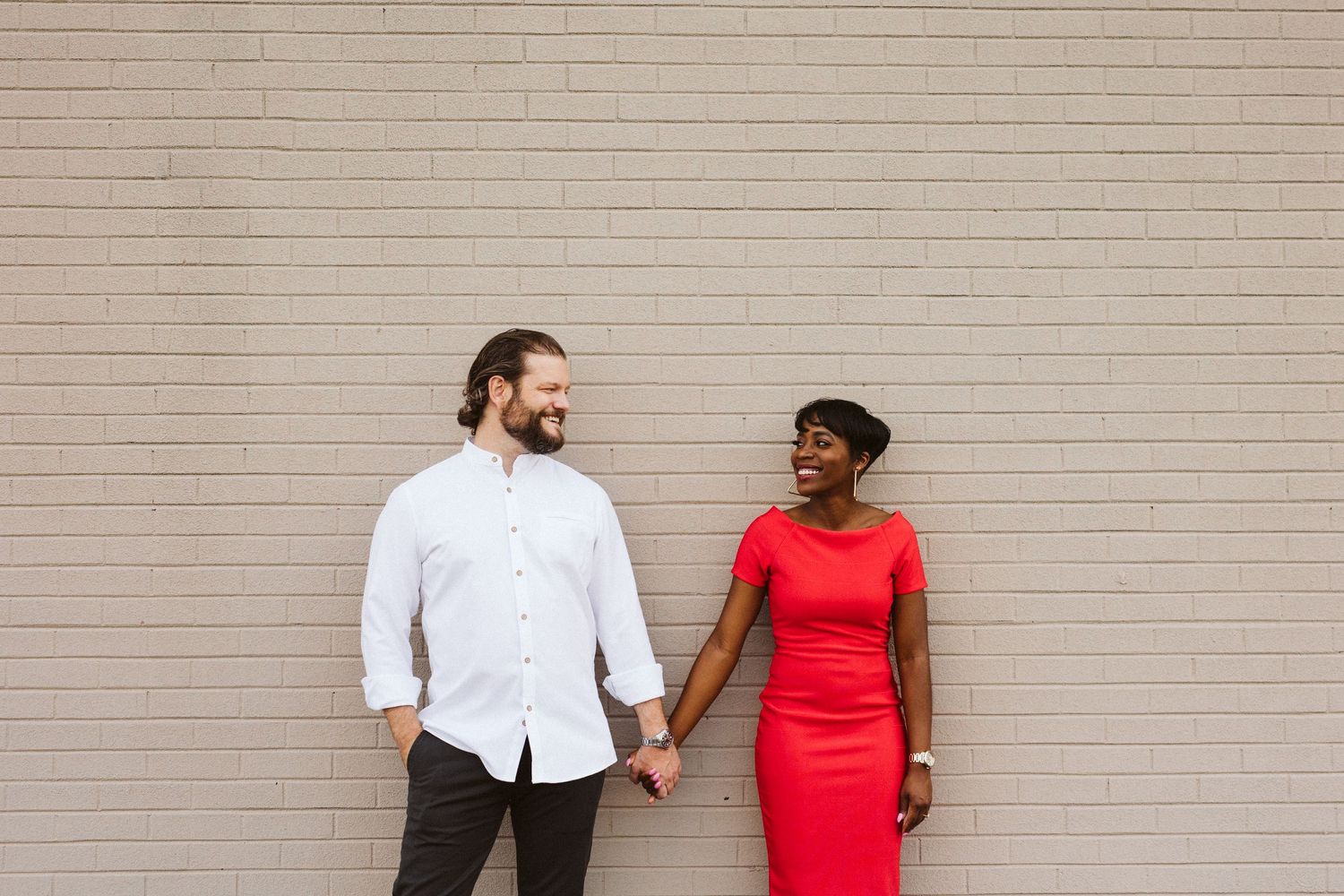 Progressive sequence of a couple interacting against a minimalist white brick wall.