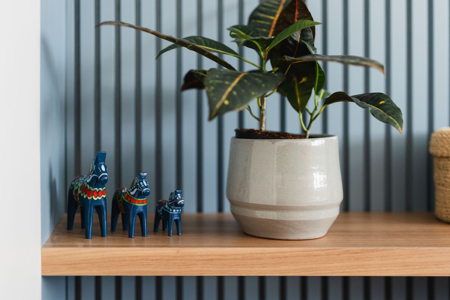 Decorative shelf with potted plants and blue figurines against corrugated metal backdrop.
