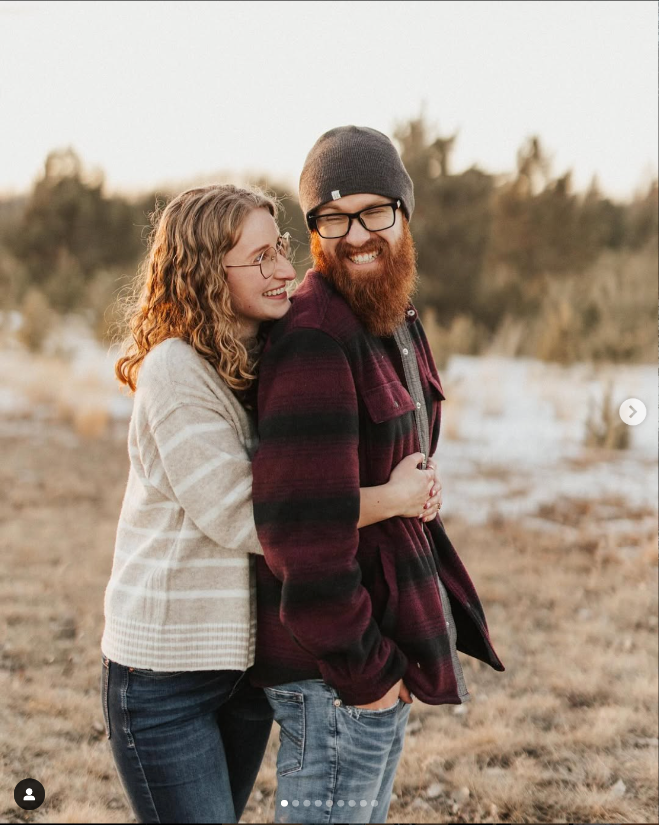 Happy couple embracing and laughing in casual clothing during sunset outdoor photoshoot.