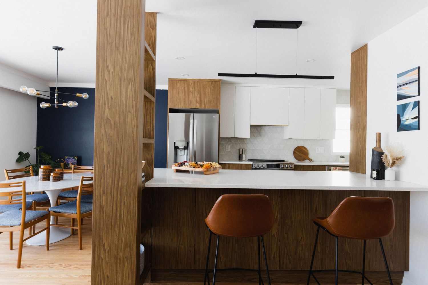 Open concept kitchen and living space with wood accents and modern pendant lights over island counter.