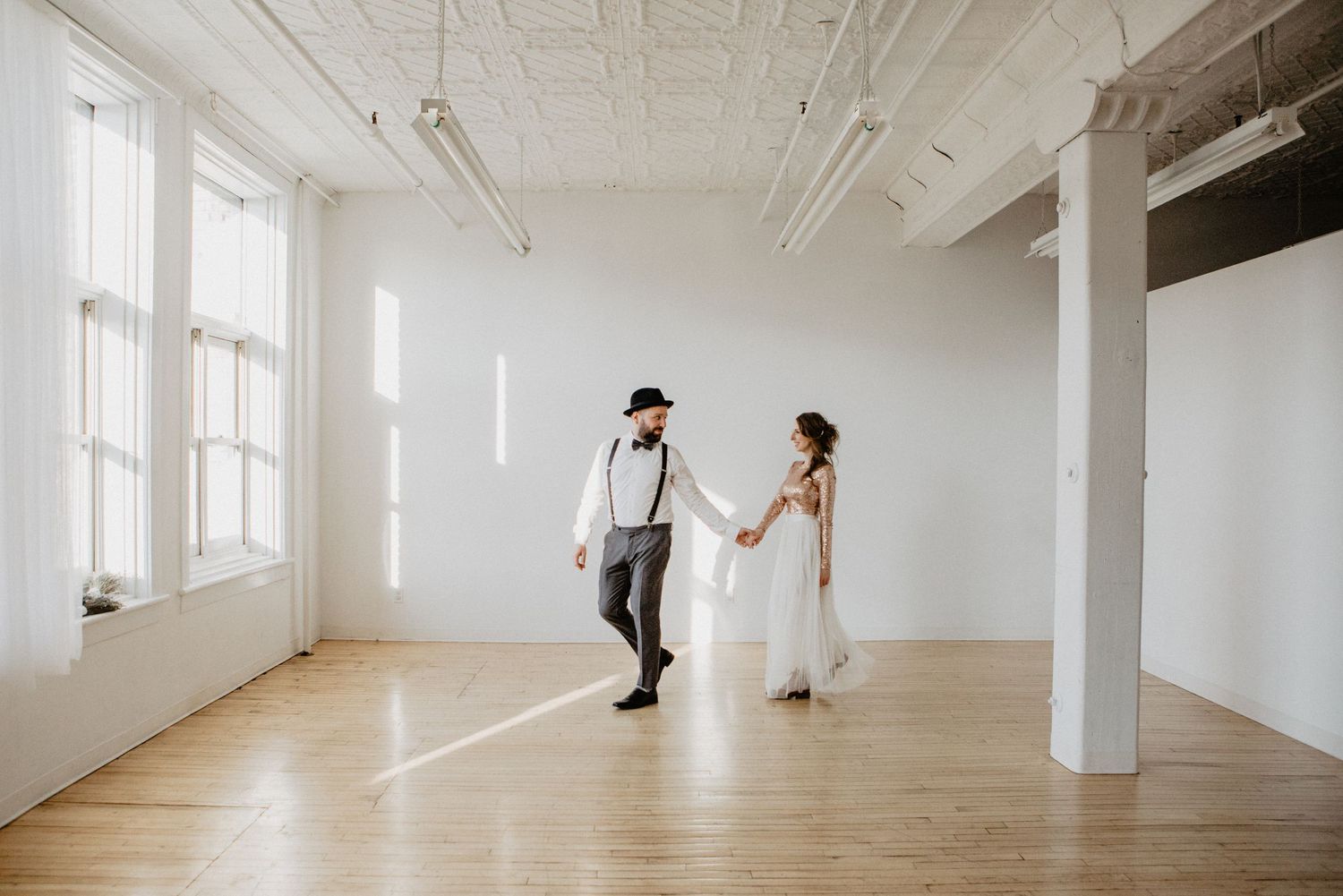 Modern white event space with industrial columns and large windows letting in natural light.