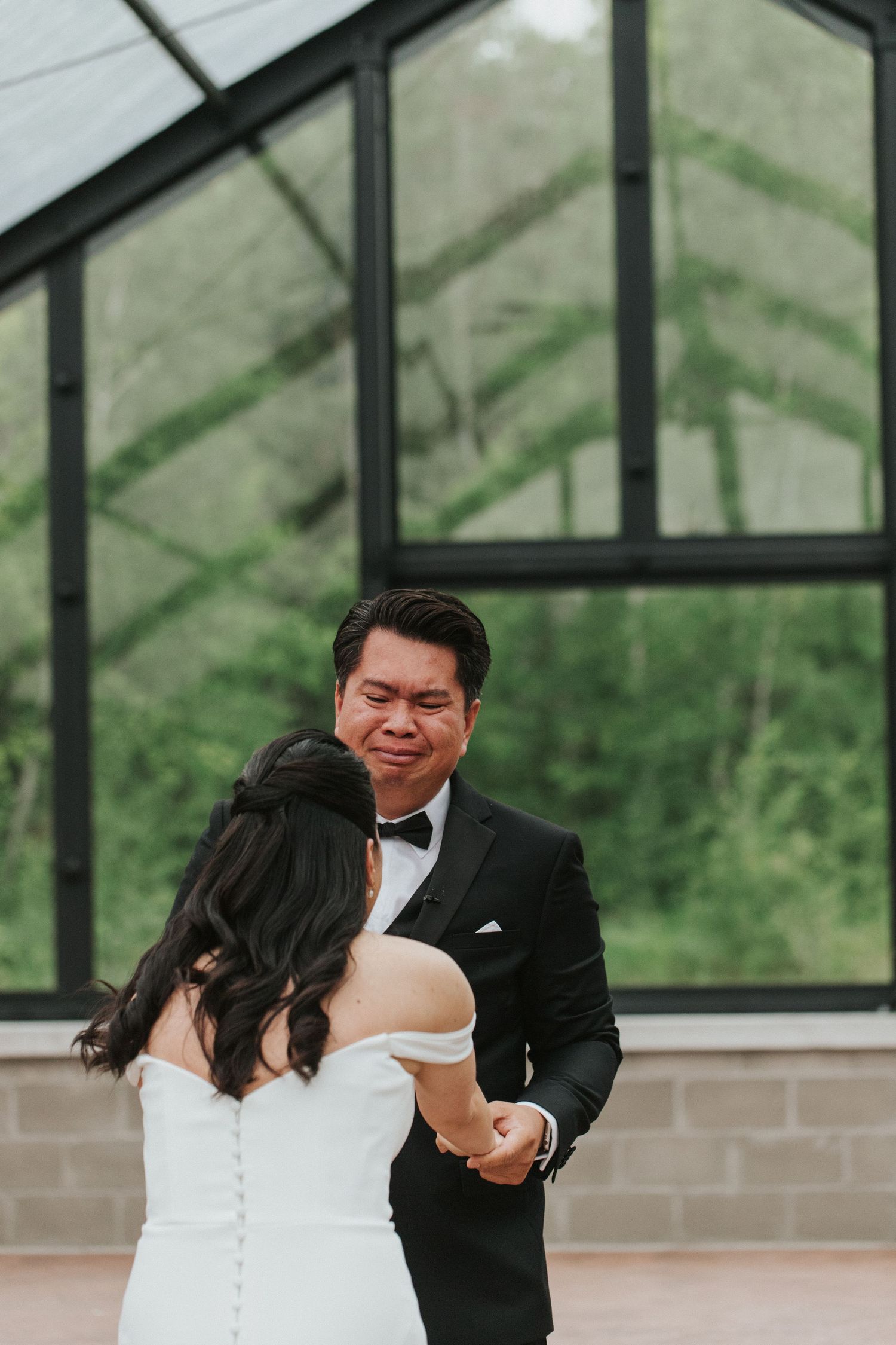 Newlyweds share their first dance in an elegant greenhouse setting with natural lighting.