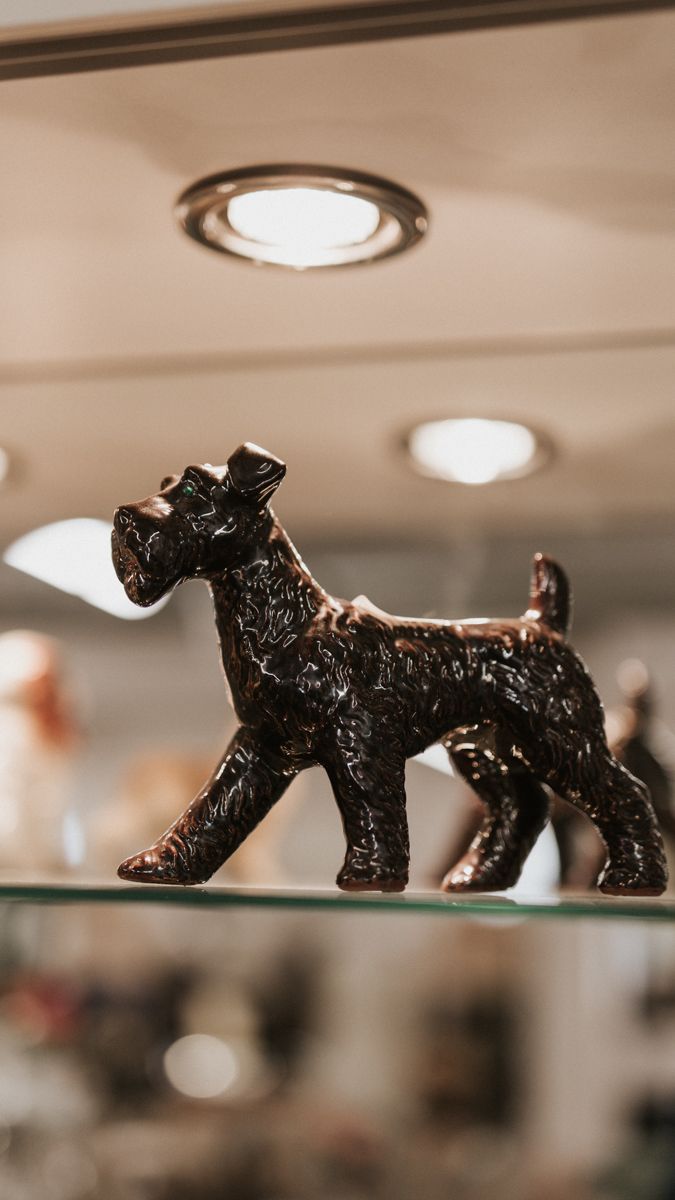 Black decorative scottie dog figurines arranged on a glass display shelf.