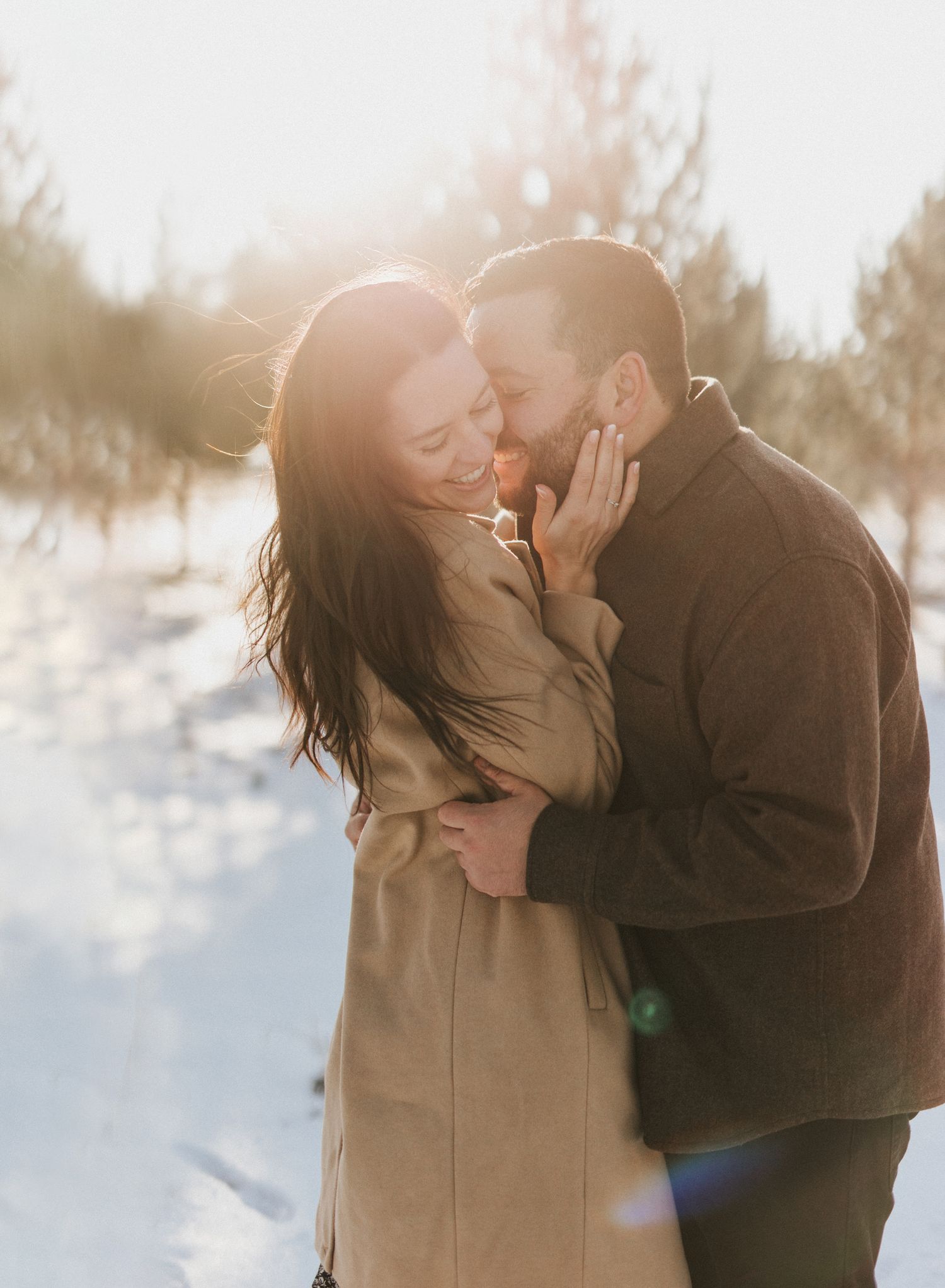 Soft sunlit winter scene captures romantic moment between couple in warm coats.