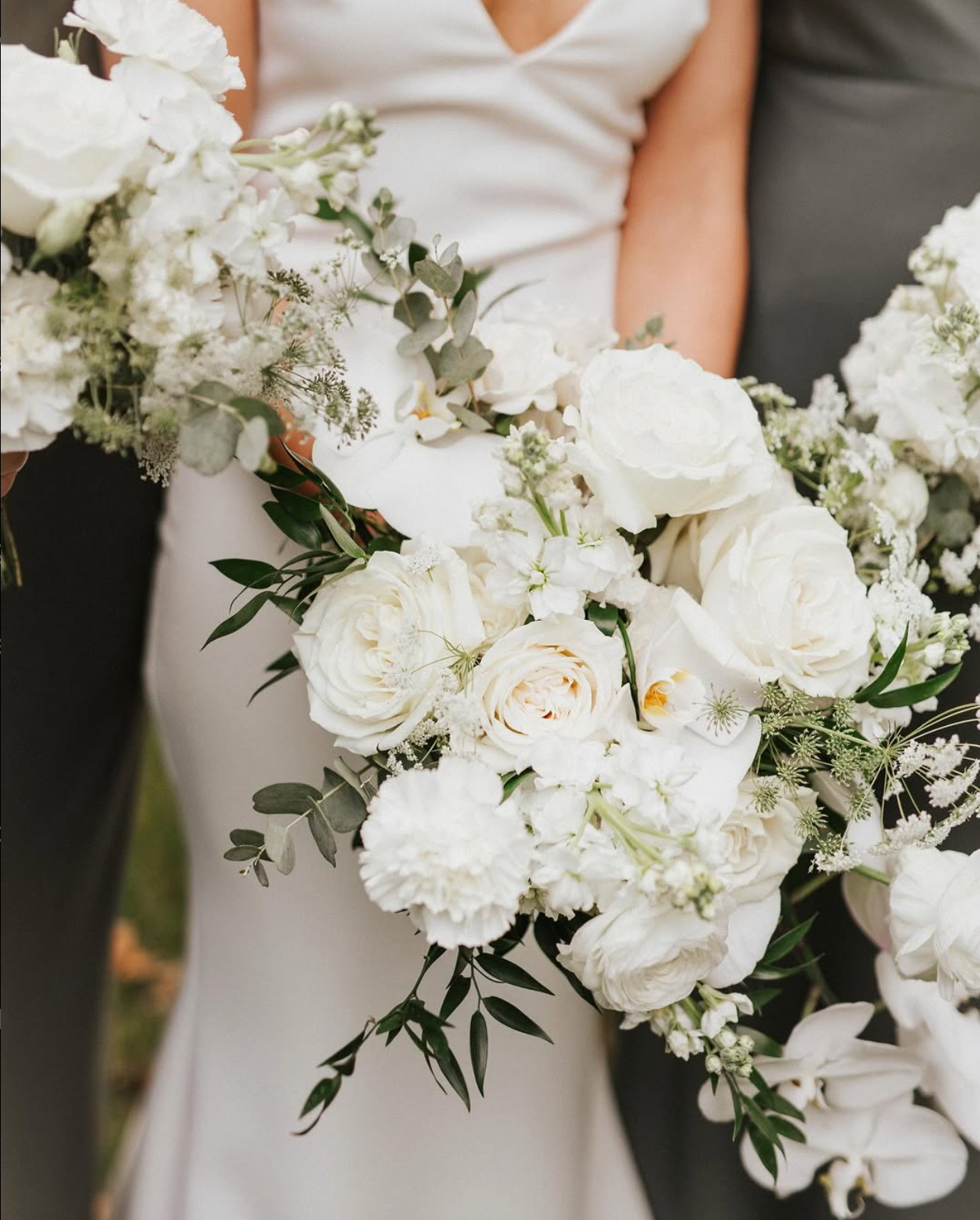 Elegant white floral wedding bouquet with roses and delicate greenery.