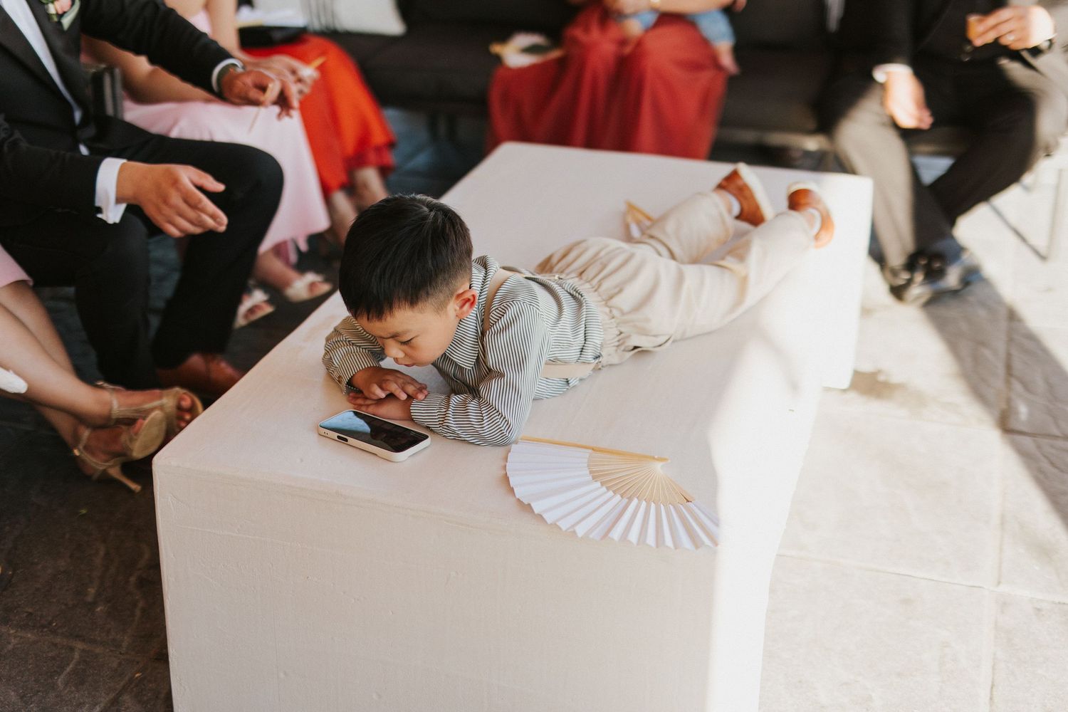 Wedding guests signing a guestbook with white paper fans displayed on a dark wooden table.