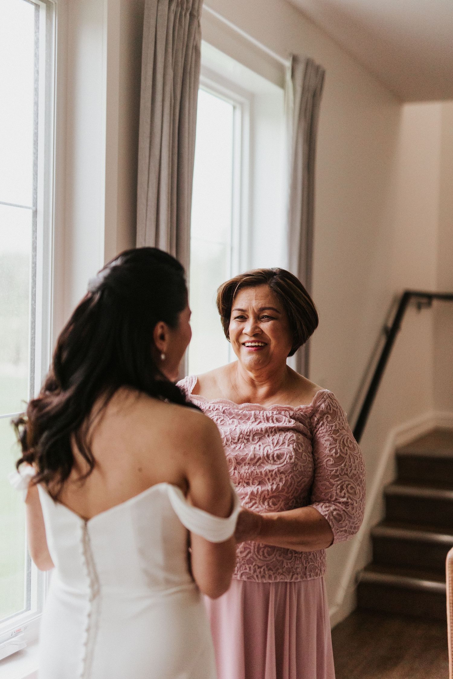 Wedding preparation scene with people sharing joyful laughter in a bright room with windows.