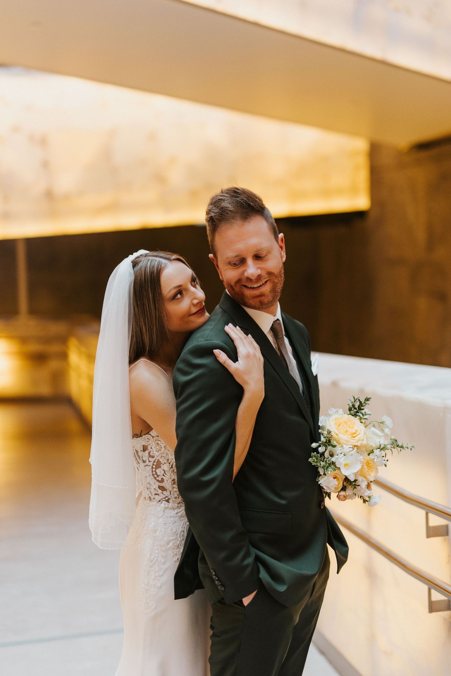 Newlywed couple sharing an intimate moment in warm golden lighting.