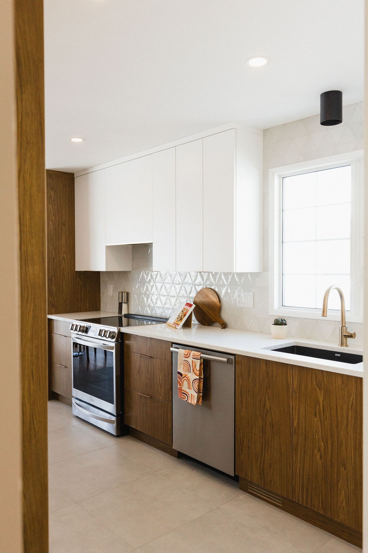 Sleek modern kitchen featuring white walls, wood cabinets, and stainless steel appliances in open layout.