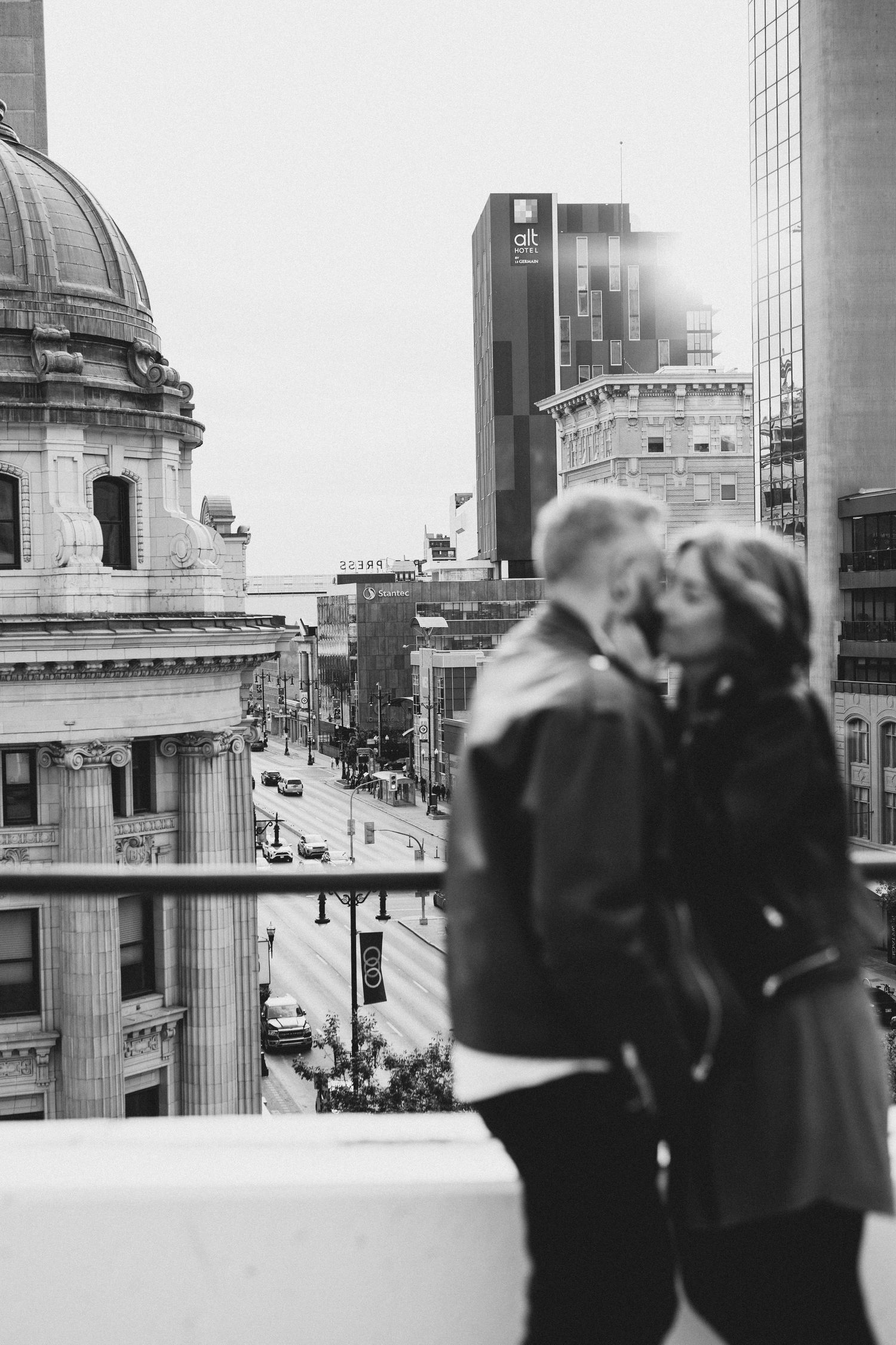 Black and white cityscape rooftop scene with figures silhouetted against urban architecture.