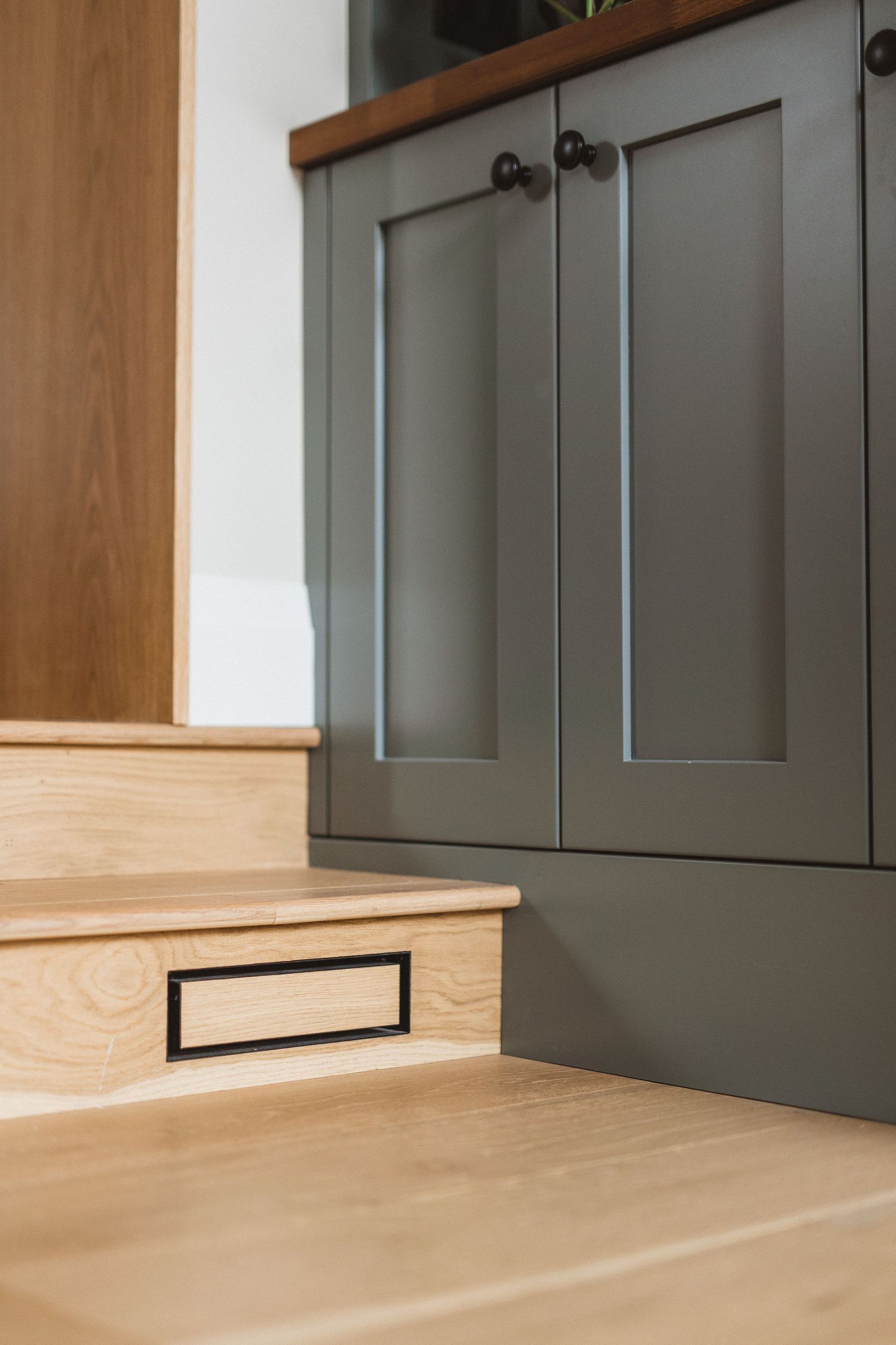 Gray cabinet doors with wood trim and baseboards in modern home interior.